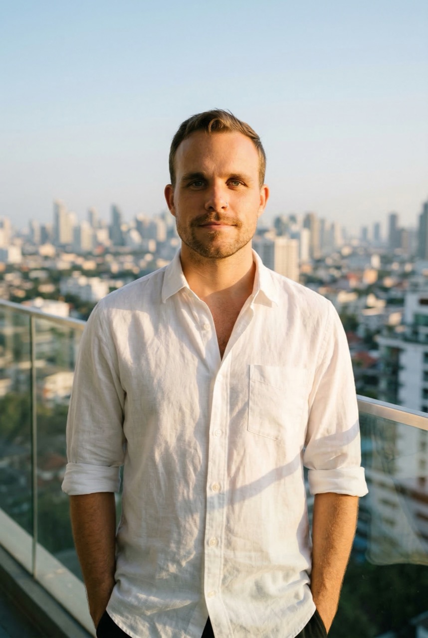 Jon Dallas on a balcony with city skyline at golden hour